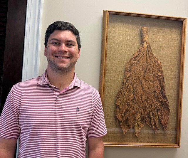 Judd Price standing in front of dried tobacco plant.